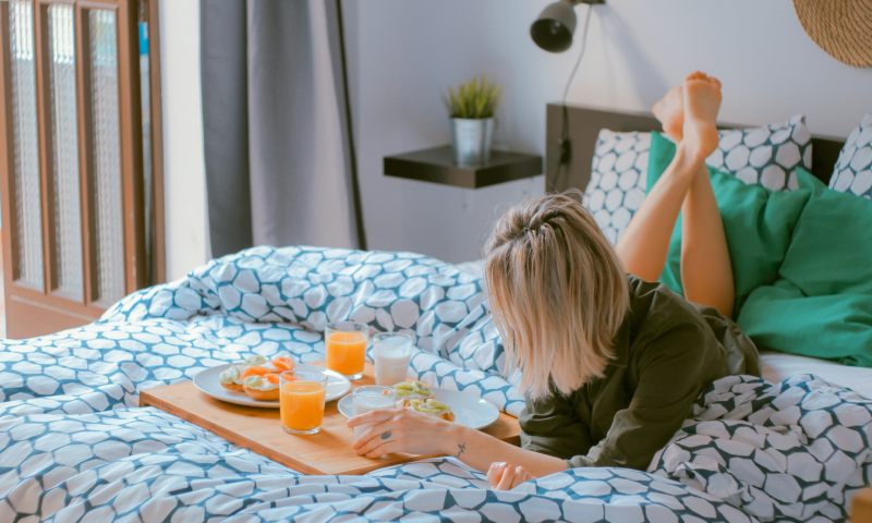 Ragazza sul letto che fa colazione in un B&B